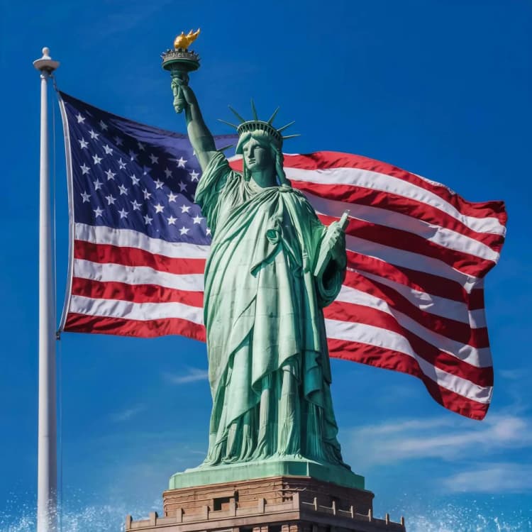 Statue of Liberty with American flag waving under clear sky